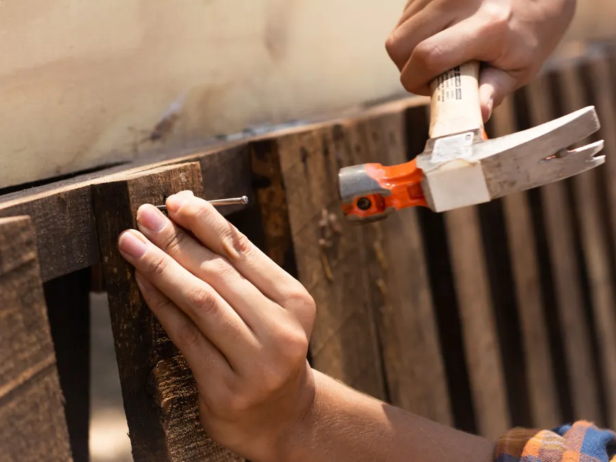 Hammering a nail into a wooden fence board